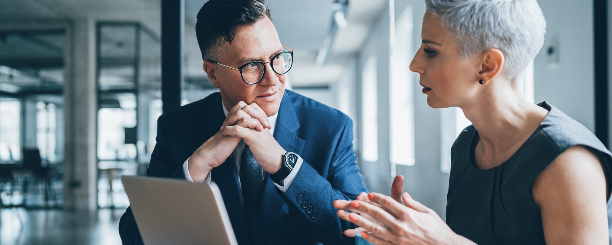 Business man and woman discussing finances in front of computer